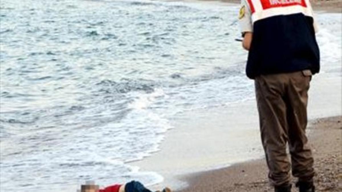 El niño sirio Aylan Kurdi, ante un guardacostas en la playa de Turquía a la que llegó su cadáver.