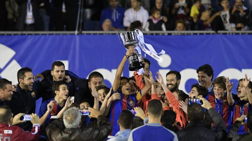 Los jóvenes futbolistas del Barça alzan el trofeo.