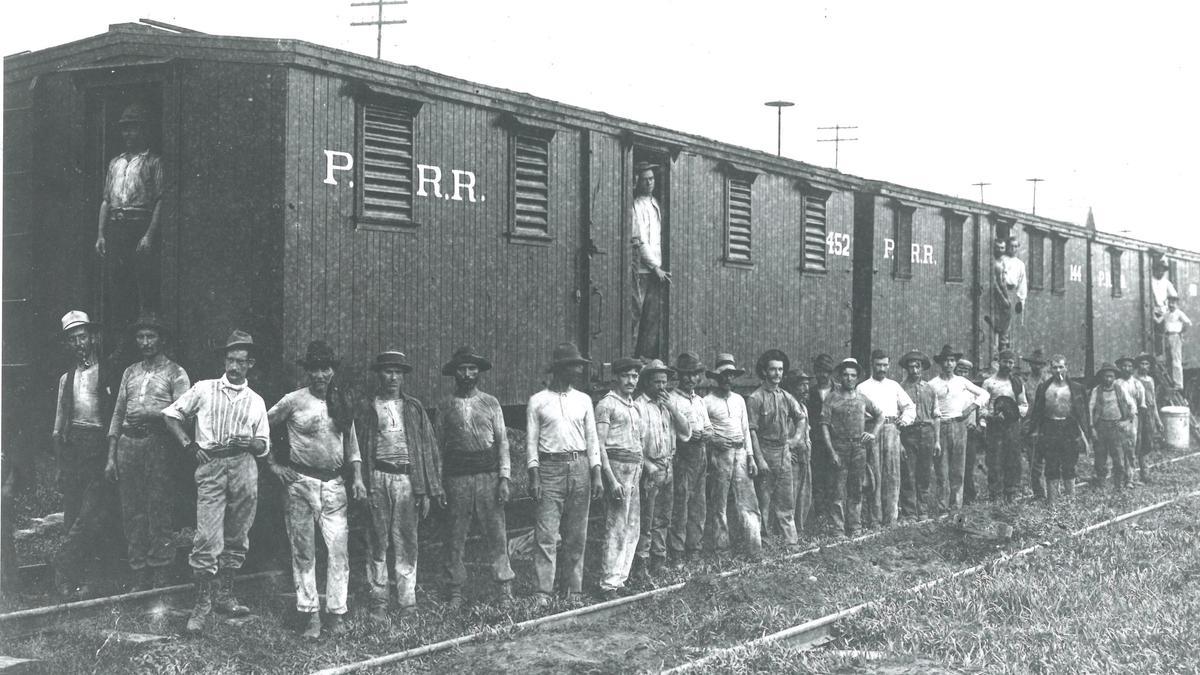 Un grupo de trabajadores gallegos del canal de Panamá delante de los vagones del ferrocarril en los que dormían