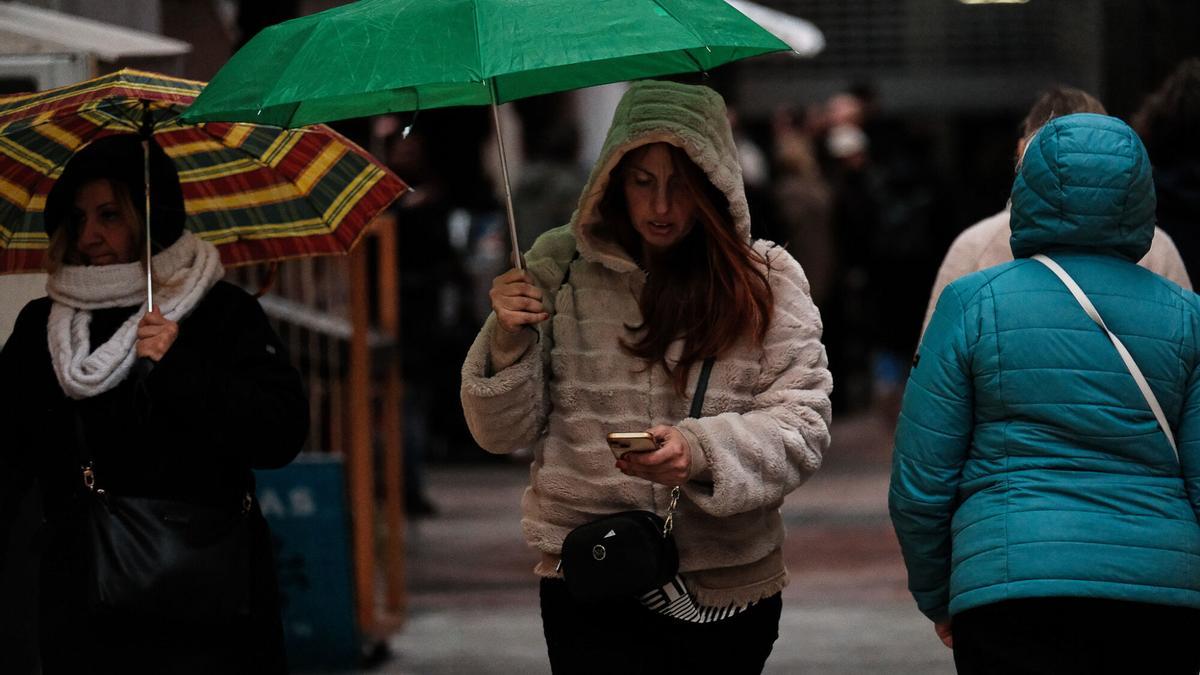 Una mujer se refugia bajo su paraguas en una imagen de archivo.