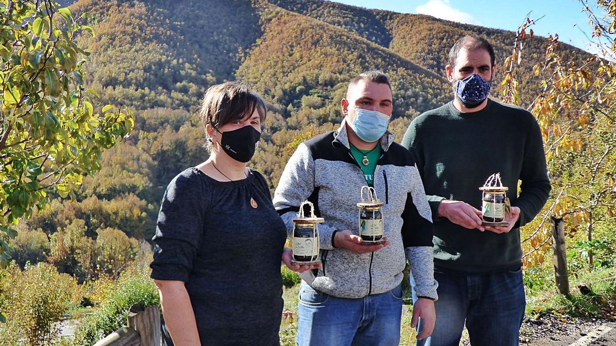 Por la izquierda, Rosa Rodríguez y Víctor García, cuñada y sobrino de Victorino García, y Alberto Uría, con los tarros de miel en su recuerdo en la mano, ayer en Trabáu. En el círculo, el tarro de “Miel del Cortín”. | |  D. Á.