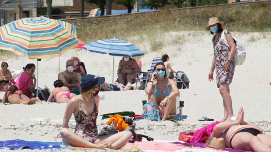 Bañistas con mascarillas en una playa de Foz.