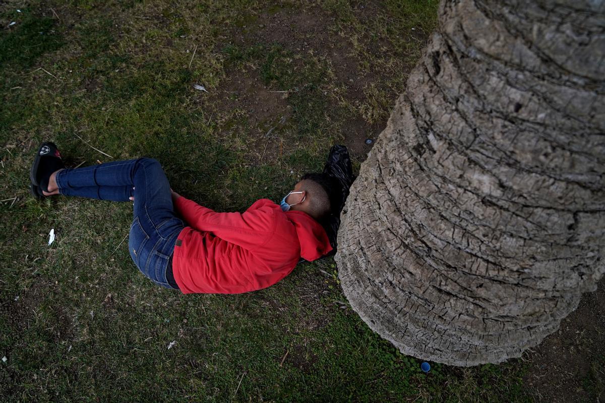 Un joven migrante duerme en un parque cercano al puerto de Ceuta.