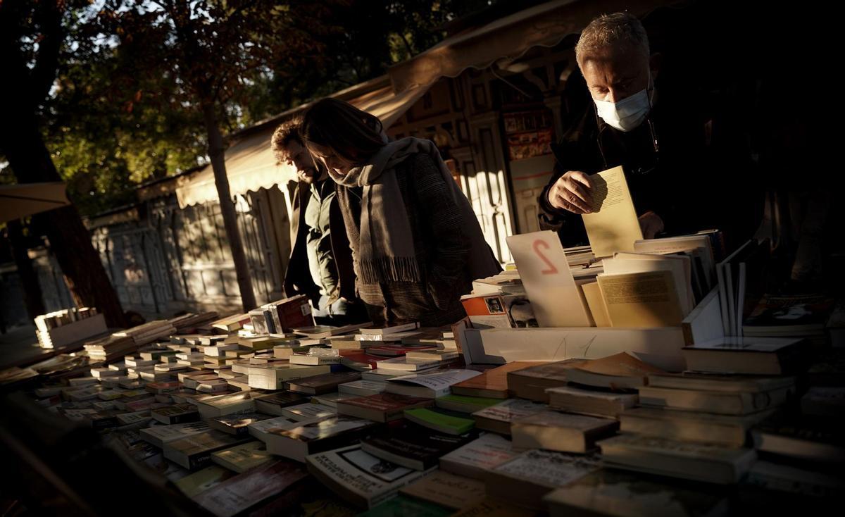 Clientes en uno de los expositores de las librerías de la cuesta de Moyano, en Madrid.