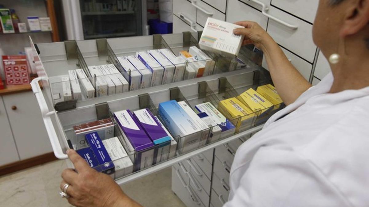 Una farmacéutica examina un cajón de medicamentos.