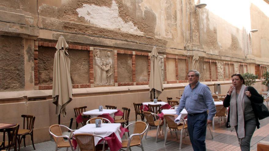 Dos repartidores pasean por la calle San Miguel junto a una de las maltrechas paredes de la iglesia de Santa María de Gracia.