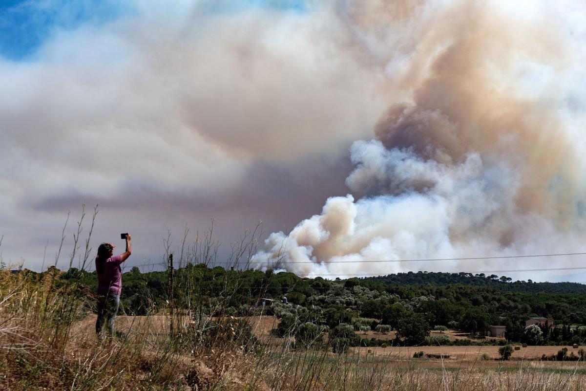 Una persona le hace una foto al humo del incendio, en La Bisbal d'Empordà.