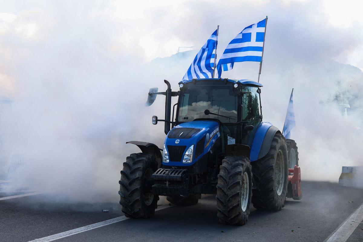 Riots police throw tear gas at farners near Heraklion International Airport, as police block the main access road in Heraklion, on the island of Crete, on December 8, 2025. Farmers on Crete on Monday clashed with riot police near the Greek islands international airports in a burgeoning protest wave related to an EU subsidy probe. (Photo by Costas METAXAKIS / AFP)