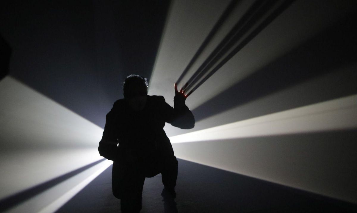 Un visitante de la exposición de Anthony McCall “rasga” la luz con sus dedos. | Fernando Rodríguez