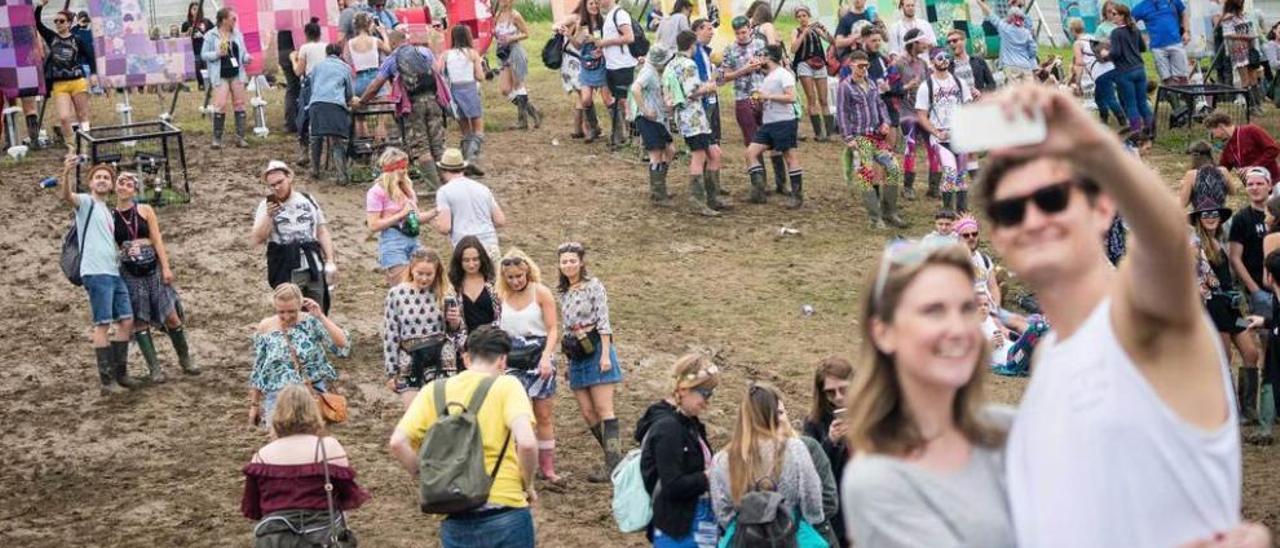 Una pareja se hace un &quot;selfie&quot; en el Festival de Glastonbury, con su recinto embarrado.