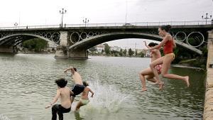 SEV08. Sevilla, 11-07-06.- Un grupo de jóvenes se lanza al río Guadalquivir a la altura del puente de Triana en Sevilla, tratando de combatir las altas temperaturas que se registran en la capital andaluza. La dirección general de Protección Civil y Emergencias mantiene la alerta en cinco comunidades autónomas, Aragón, Andalucía, Extremadura, Castilla La Mancha y Madrid, ante la persistencia de las altas temperaturas, que, según la predicción del Instituto Nacional de Meteorología (INM), comenzarán a descender desde mañana. EFE/Chema Moya. METEOROLOGIA , VERANO 2006 , TEMPERATURAS , CALOR , PAISES , ESPAÑA , ANDALUCIA, PUENTE TRIANA