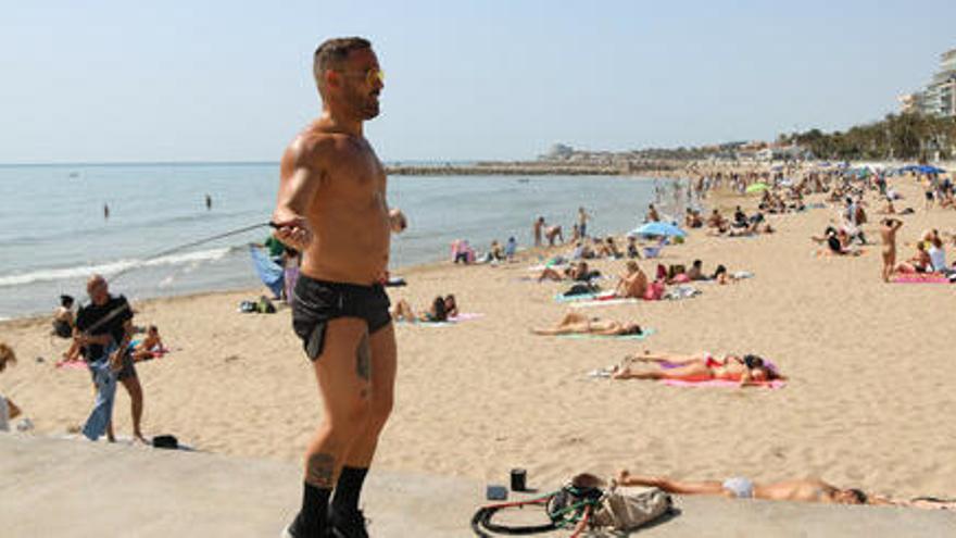 Una platja de Sitges amb un home fent exercici en primer pla