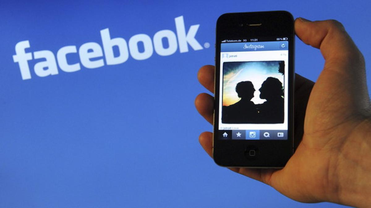 Un usuario de smartphone, delante de un logotipo de Facebook