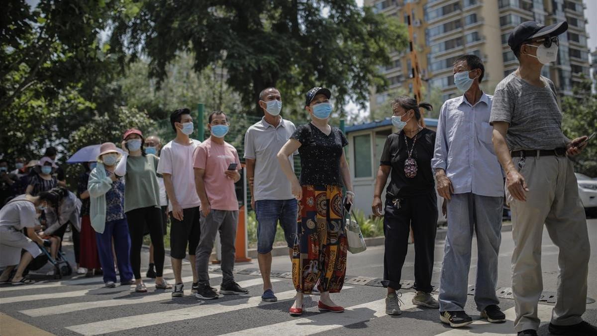 Cola de habitantes de Pekín para hacerse el test del covid-19 tras el último brote en un mercado de la capital china.