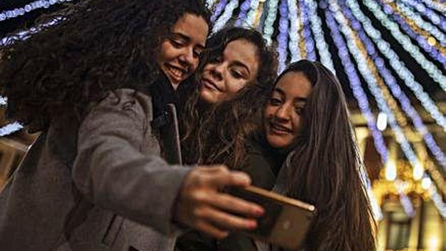 Tres jóvenes practican selfies en la Plaza Mayor.