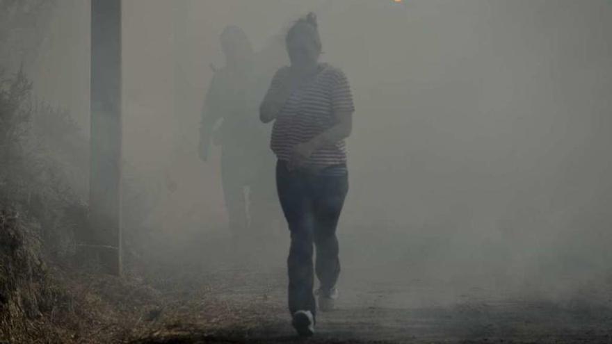 Una mujer corre escapando del humo que envolvió todo el pueblo. // Brais Lorenzo