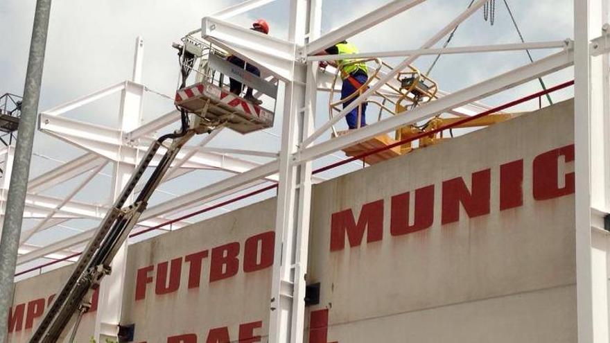 Los operarios instalando la cubierta en el campo de fútbol