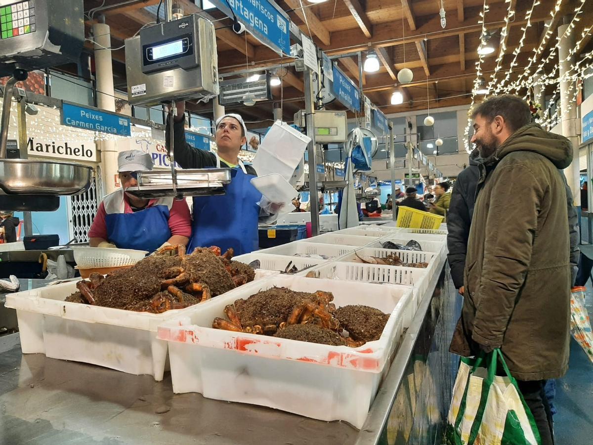 La responsable de Pescados y Mariscos Cartagena, en Bueu, atiende ayer a un cliente y en primer término las cajas con centolla a la venta.