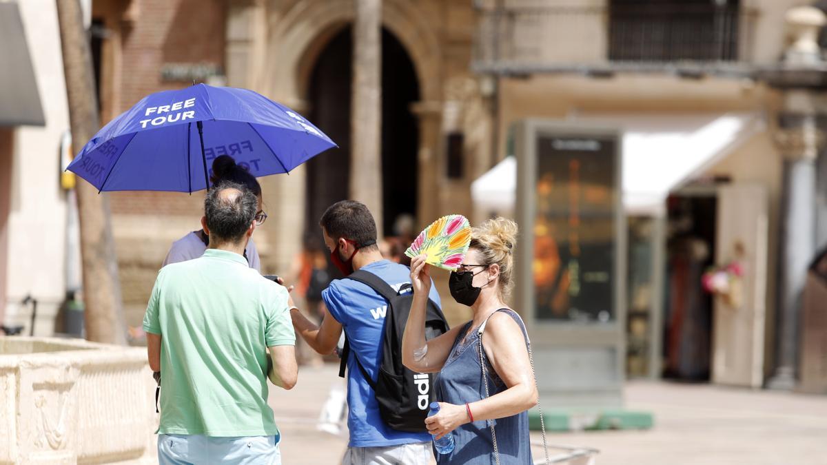 Carias personas intentando protegerse del calor en el Centro de Málaga