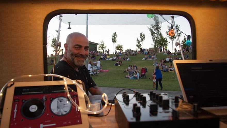 Un dj pone música al atardecer en el parque del río en una caravana