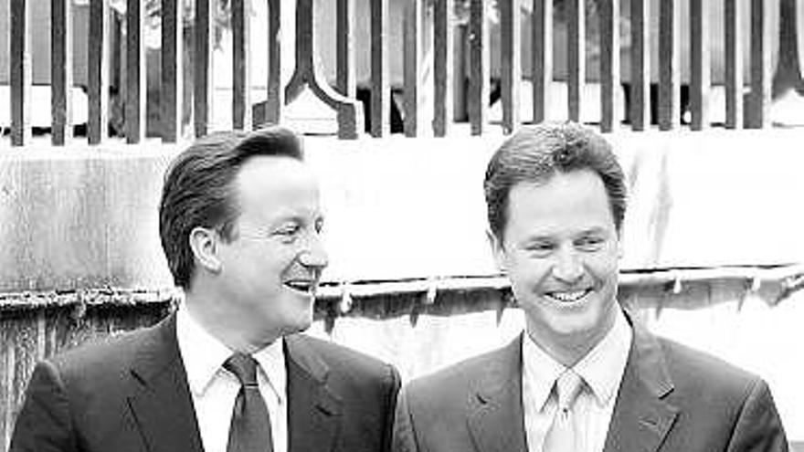 Cameron y Clegg, ayer, llegando a los jardines de Downing Street.