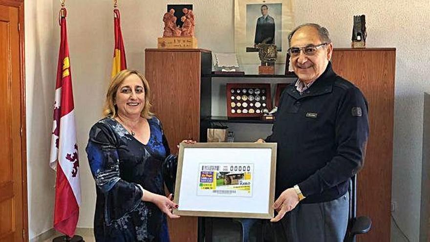 Sobre estas líneas, la directora de la ONCE en Zamora, María Ángeles Ruano García entrega una copia del cupón para el sorteo del próximo lunes al alcalde de El Cubo de Tierra del Vino, Juan Ramón García de Castro. A la izquierda, la imagen de dicho cupón ilustrado con una fotografía del parque fluvial de El Cubo, del que se repartirán 5,5 millones de copias en toda España.