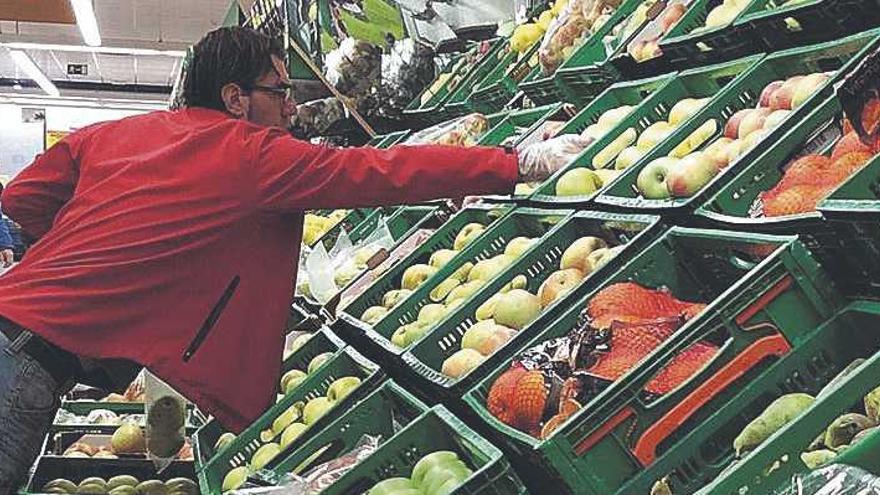 Un treballador col·loca fruita en un supermercat.