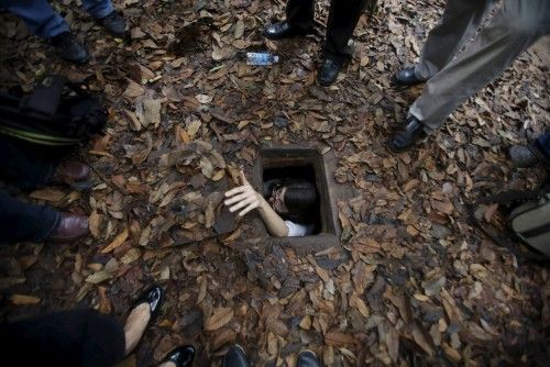 A French journalist tries to disappear into the Cu Chi tunnel network through a hole camouflaged on the jungle floor during a guided tour near Ho Chi Minh City