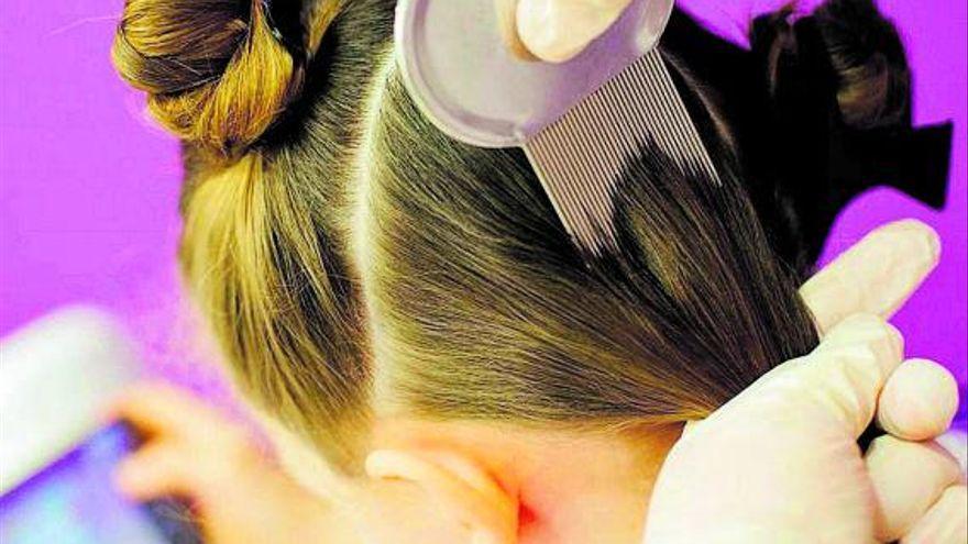 Cepillado del cabello de una niña con un peine para arrastrar piojos.