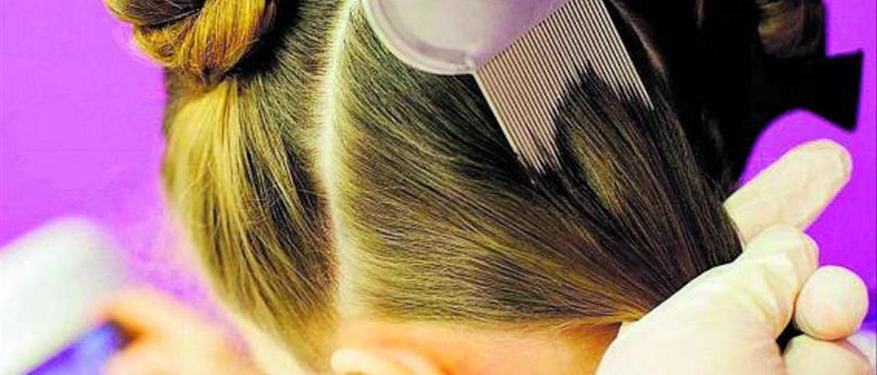 Cepillado del cabello de una niña con un peine para arrastrar piojos.