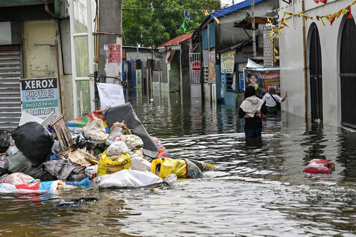 La gente camina a través de una calle inundada después de las fuertes lluvias traídas por el monzón del suroeste en Pampanga el 31 de agosto de 2026. (Foto de Jam STA ROSA / AFP)