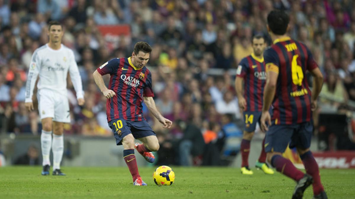 Messi envía el balón a Xavi ante Cristiano Ronaldo y Mascherano, en el pasado Barça-Madrid.