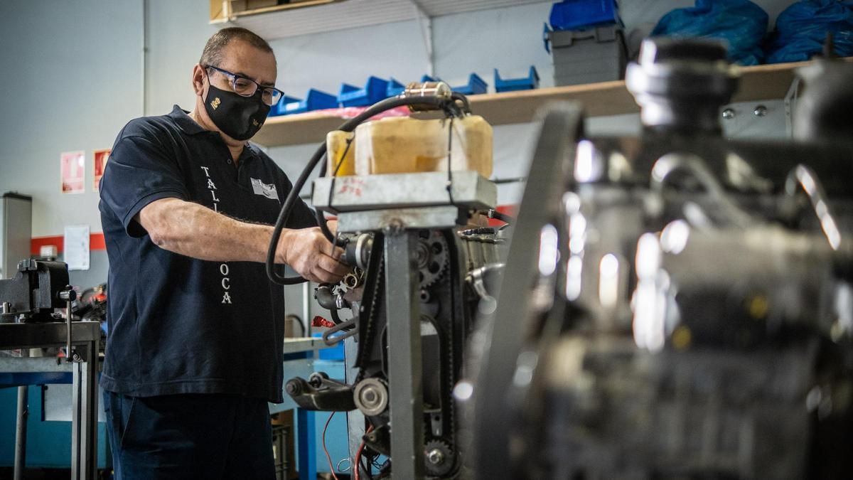 El mecánico Francisco Roca repara el motor de un vehículo en su taller.