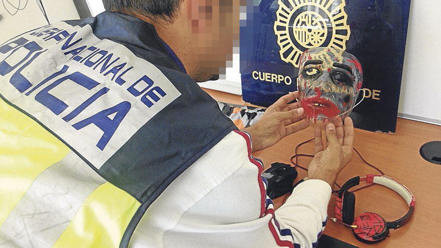 Un policía muestra la careta incautada a los detenidos.