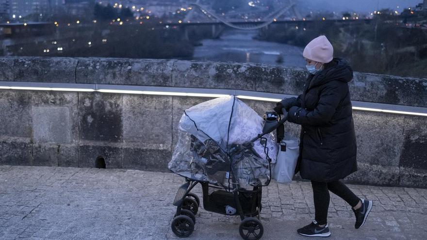 Una mujer pasea con un carrito con mascarilla y protegida del frío, en Ourense