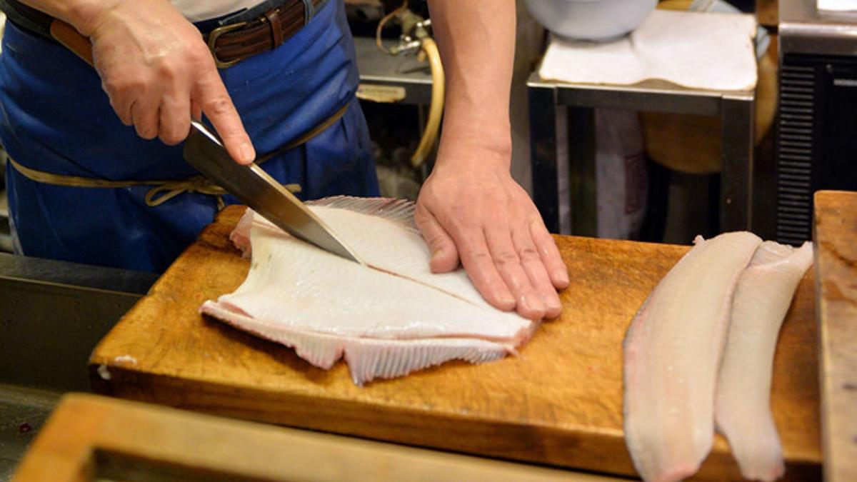 Un cocinero trabajando con un bacalao fresco.