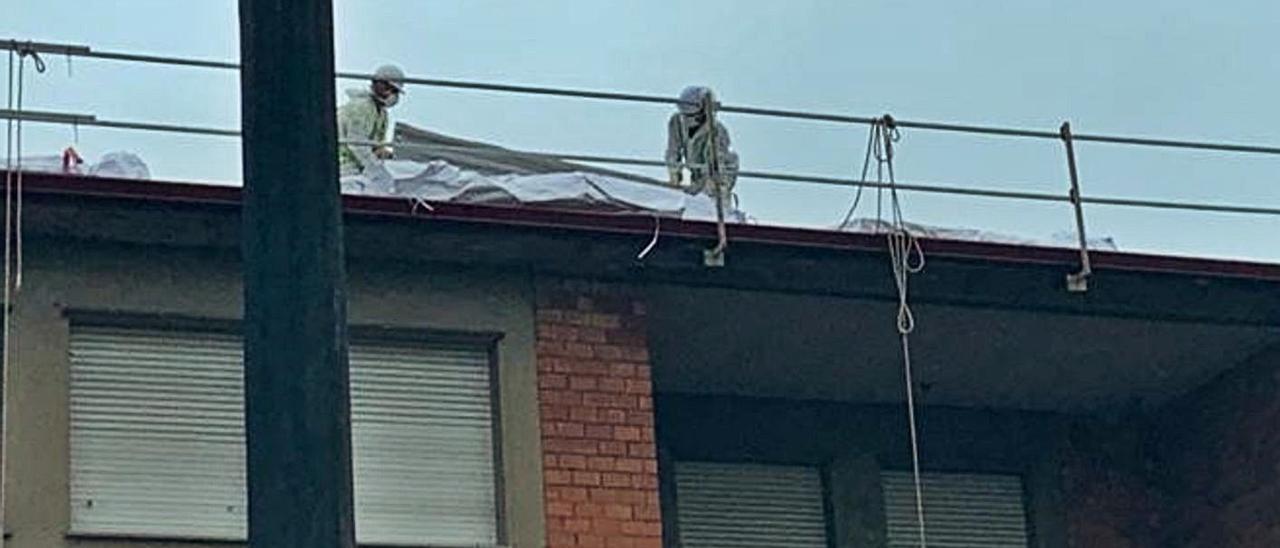 Dos operarios, trabajando ayer en la cubierta del colegio de Turiellos.