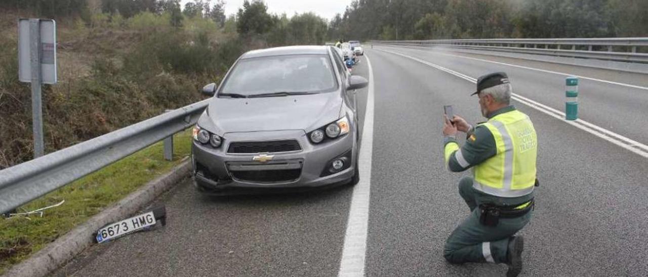 Un agente de Tráfico con el coche que impactó contra el perro en el Corredor en Meira. // Santos A.