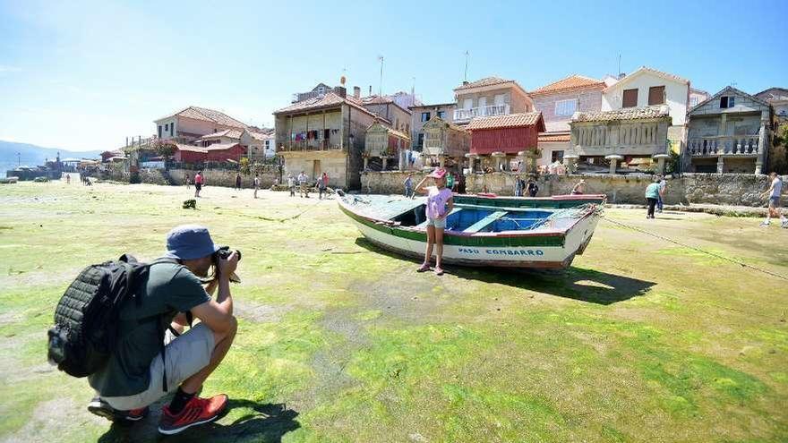 Turistas en la playa de Pinela sacando fotografías con los hórreos de Combarro al fondo. // Gustavo Santos