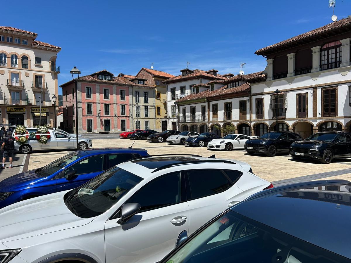 Varios vehículos de la marca Porsche frente a la iglesia de Pravia para despedir al fallecido.