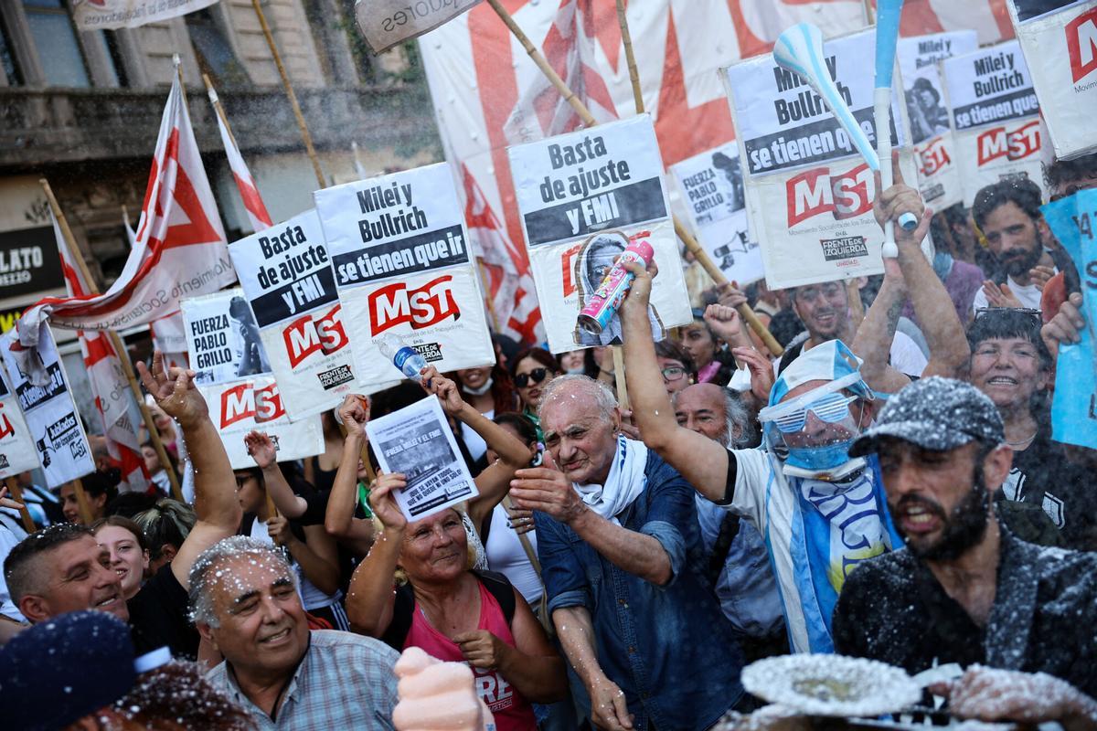 Manifestantes muestran una pancarta y carteles, mientras trabajadores argentinos, y movimientos sociales se unen a la protesta semanal de jubilados contra las políticas de ajuste del presidente argentino Javier Milei, cerca del Congreso Nacional, en Buenos Aires.