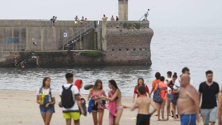 Al fondo, bañistas, ayer, en la zona del muelle del Gayo, en Luanco.