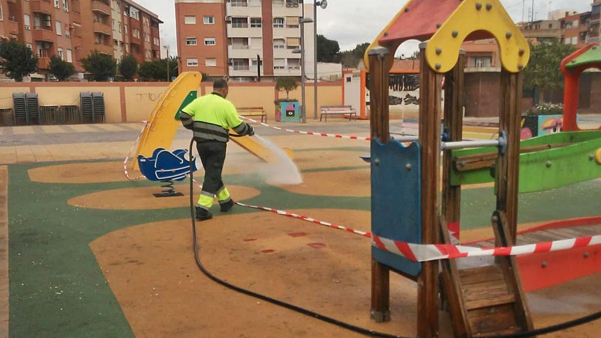 Un operario de la limpieza realiza un baldeo en un parque infantil de Sant Joan.