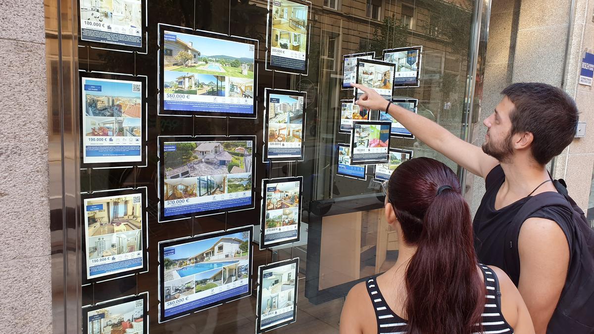 GENTE VIENDO EL ESCAPARATE DE UNA INMOBILIARIA.