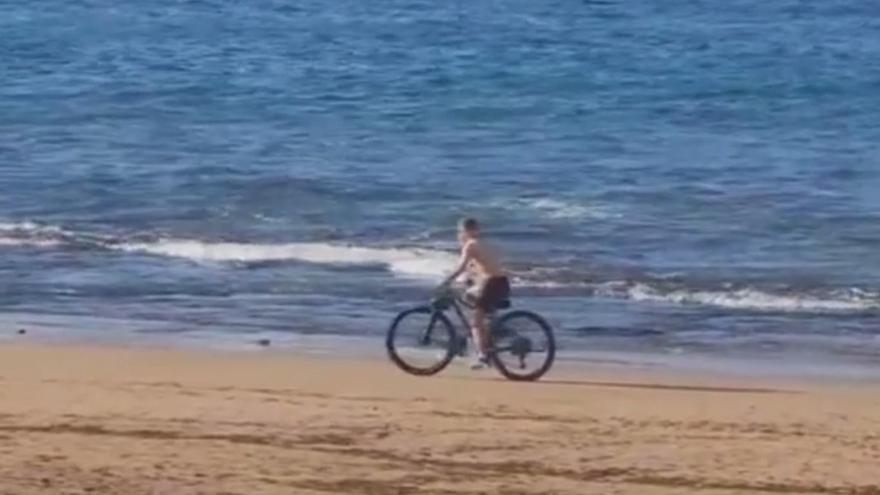 Circula con su bici por plena playa de Las Canteras