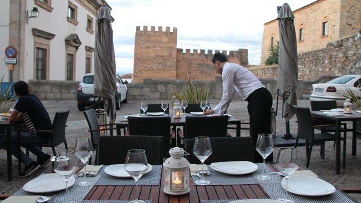 Un profesional de hostelería prepara una terraza del casco viejo, en Cáceres.