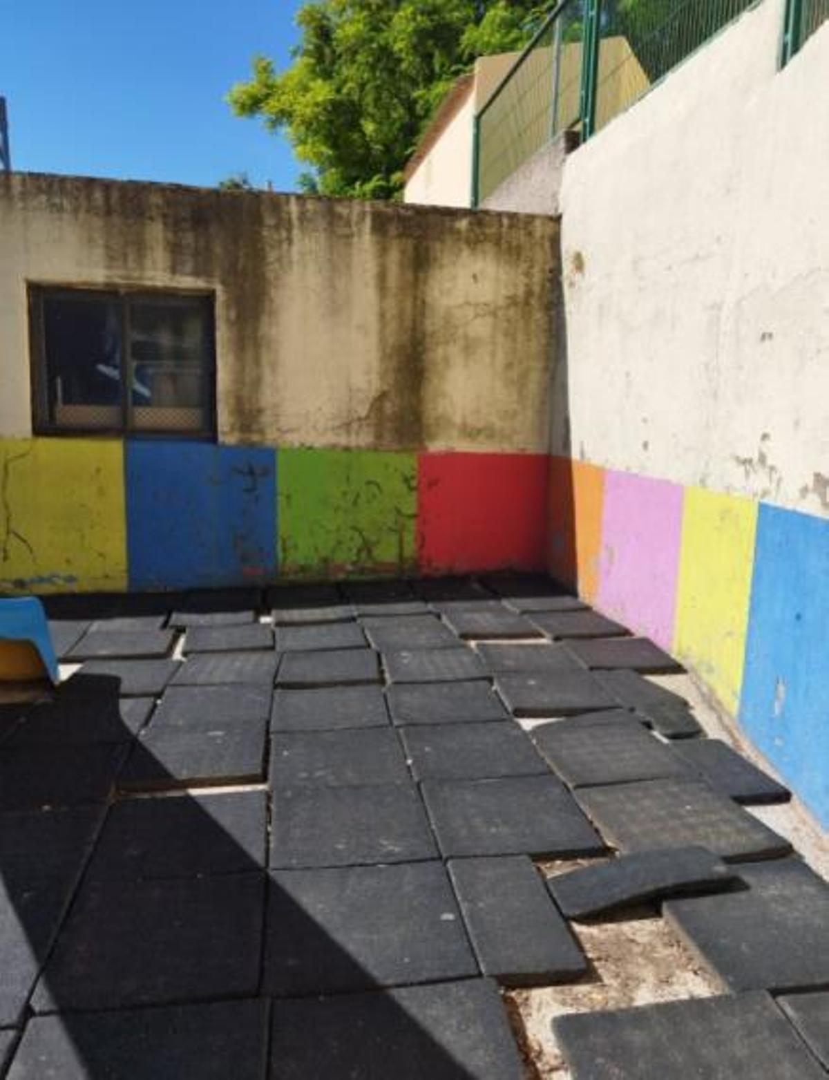 Patio de infantil , con losas de caucho sueltas y paredes con desconchados por la dana.