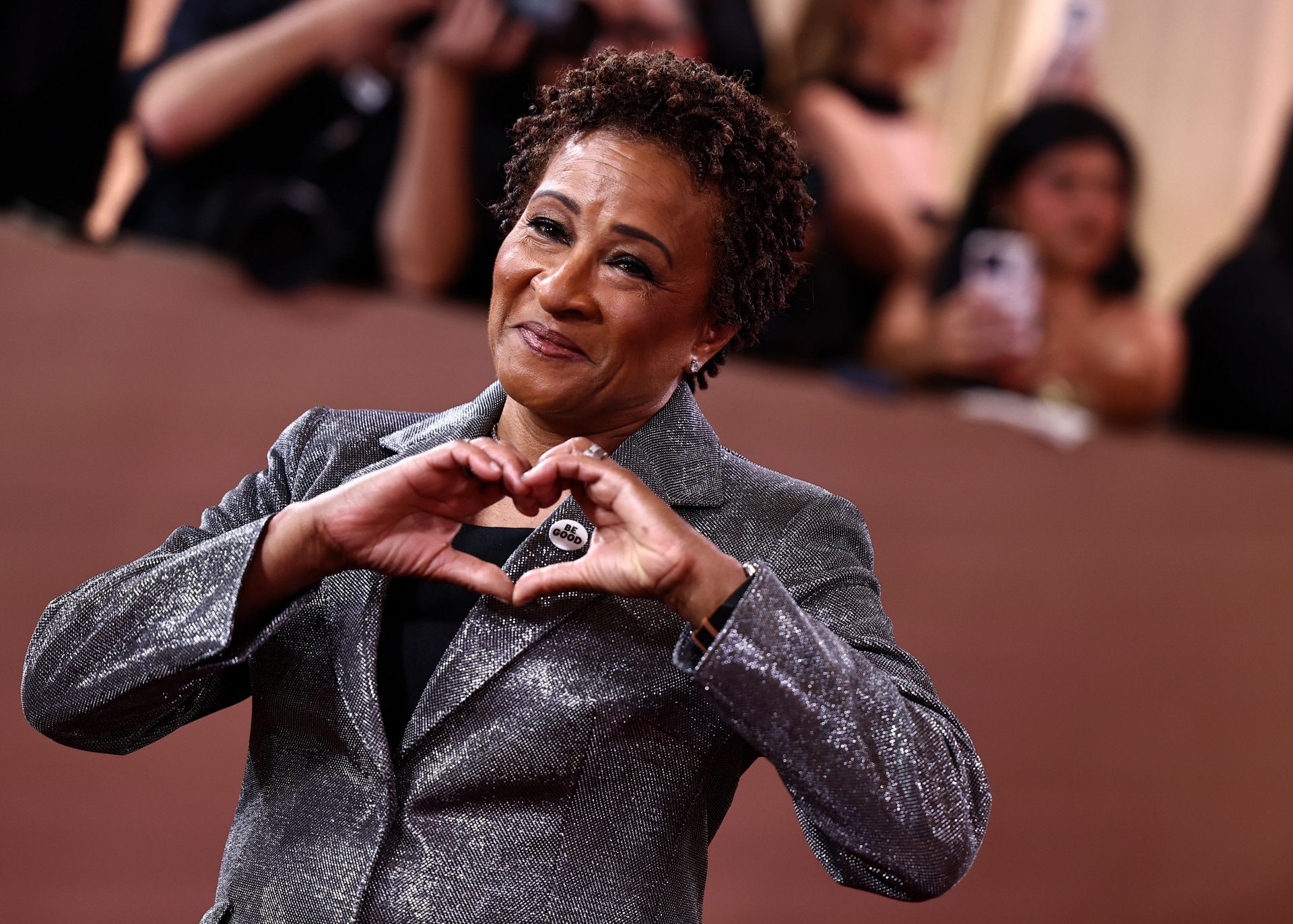 Wanda Sykes haciendo un 'cuore' mientras luce el pin de 'Be Good'