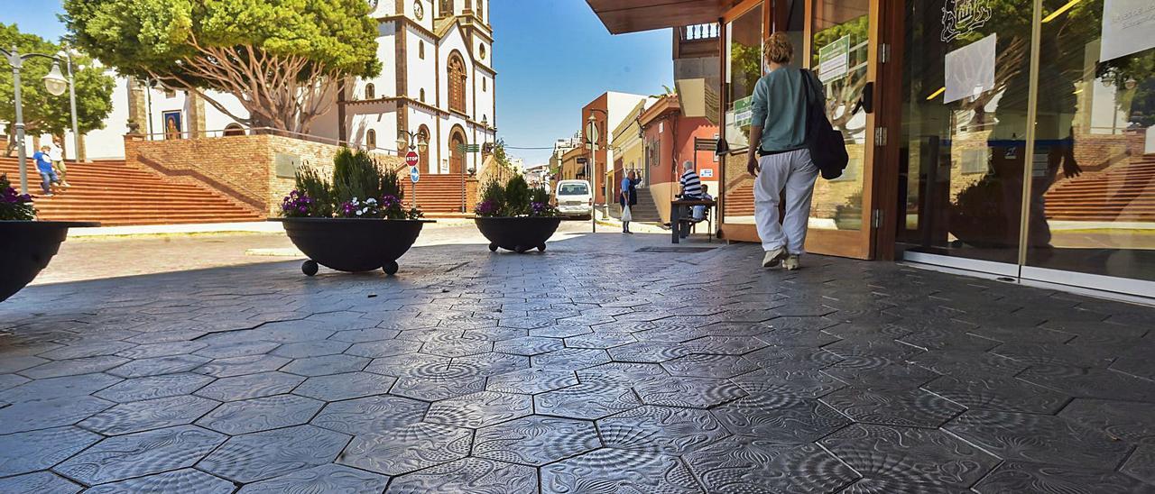Un peatón camina en la acera del Ayuntamiento, con baldosas del boceto de Antoni Gaudí, con la plaza y la iglesia de la Candelaria, a la izquierda y al fondo | | ANDRÉS CRUZ