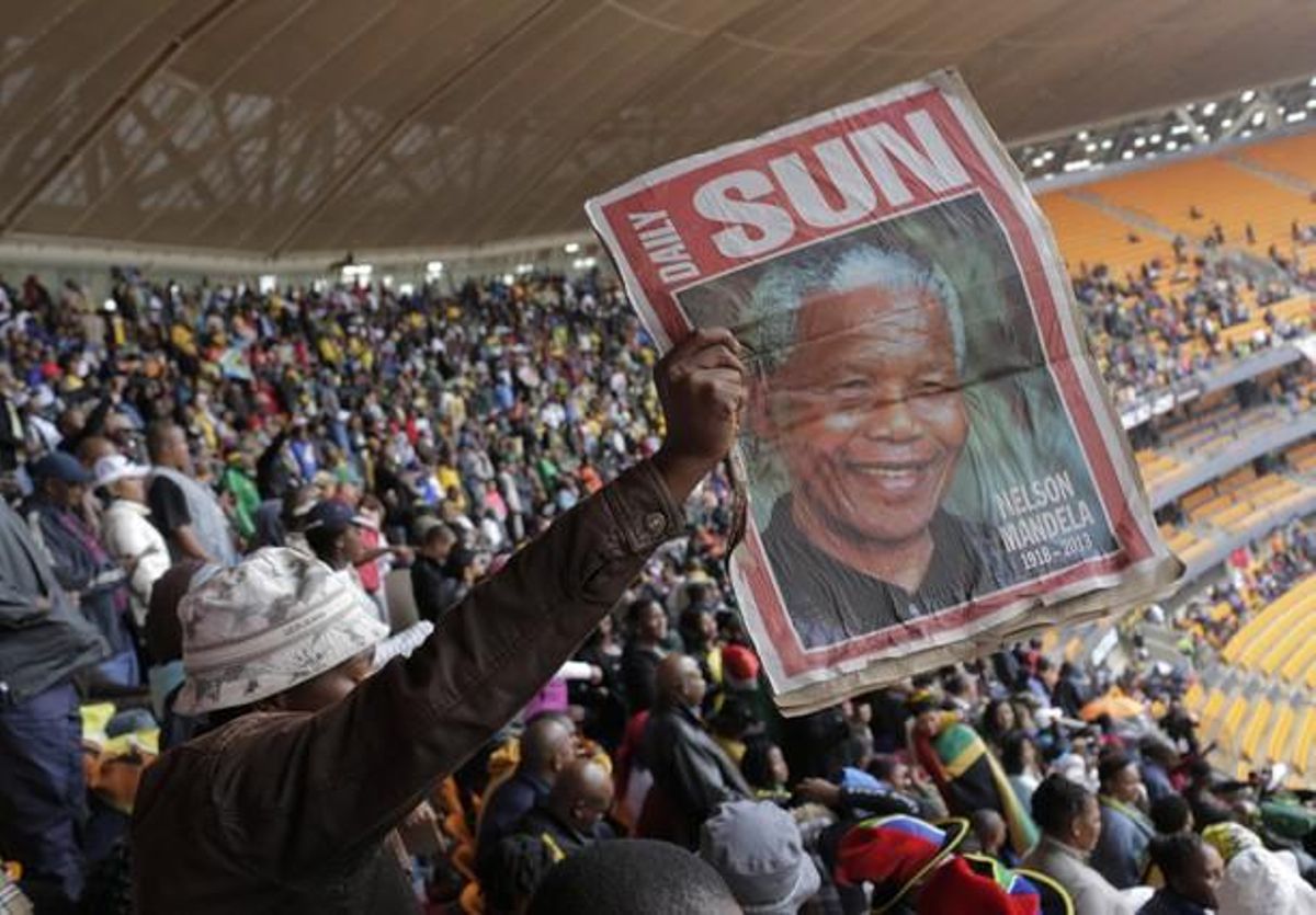 Un home sosté una foto de Mandela, a l’estadi FNB.